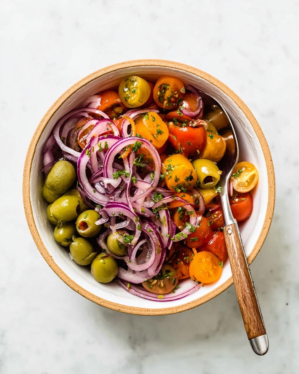 A white bowl with a light brown rim holds a fresh salad made of three visible layers: the bottom layer is bright green whole olives, the middle layer consists of halved cherry tomatoes in orange, yellow, and red hues, and the top layer features thin, curly rings of purple-red onion mixed with chopped green herbs. A metal spoon with a wooden handle rests inside the bowl, angled toward the right side. The bowl sits on a white marbled surface. photo taken with an iphone --ar 4:5 --v 7