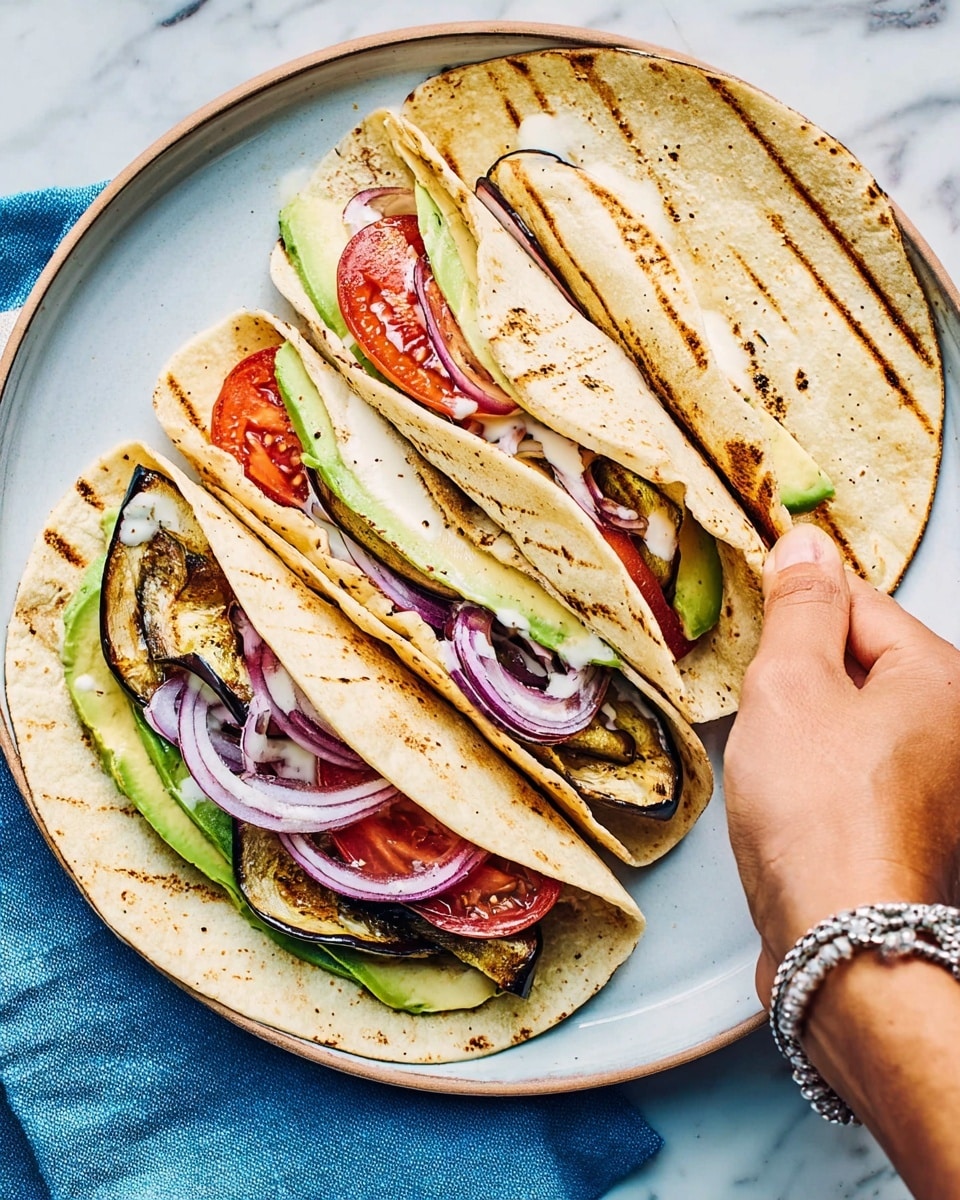 Three folded tortillas are placed on a round white plate set on a white marbled surface with a blue cloth partly visible. Each tortilla is toasted light brown with visible grill marks and folded to show three layers inside. The bottom layer has green avocado slices and grilled brown eggplant pieces. The middle layer contains thin slices of red onion. The top layer includes thick red tomato slices, all lightly drizzled with white sauce. A woman's hand with a silver bracelet is reaching to hold the tortilla on the right side. Photo taken with an iphone --ar 4:5 --v 7