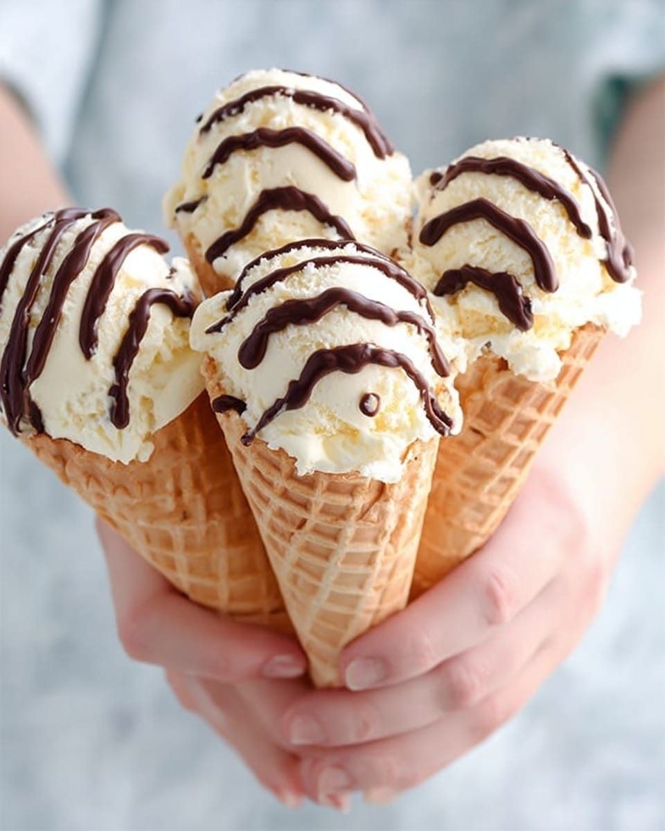 The image shows three waffle cones held close together by a woman's hand against a white marbled background. Each cone has one large scoop of creamy vanilla ice cream with a smooth texture, topped with thick, dark chocolate drizzle in wavy lines. The cones have a light golden color and a crisp, grid-like pattern. Photo taken with an iphone --ar 4:5 --v 7