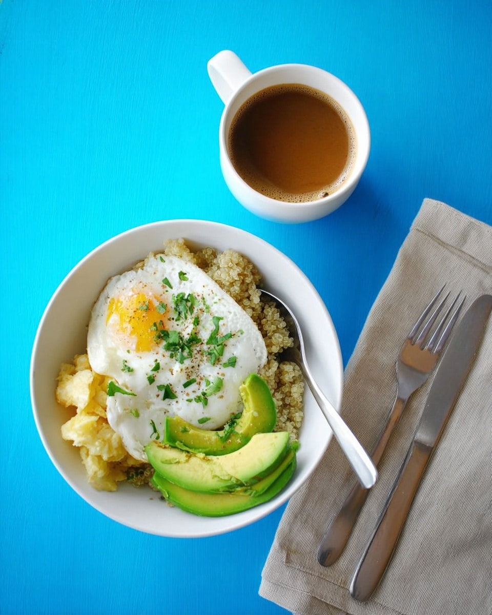 A white bowl contains a meal with four layers: the bottom layer is light brown quinoa, topped with light yellow scrambled eggs, then bright green sliced avocado on one side, and a white fried egg with a slightly runny yolk in the center, sprinkled with green herbs. A silver spoon rests inside the bowl on the right side. Next to the bowl is a white cup filled with brown coffee, all placed on a bright blue surface. A beige cloth napkin with a silver knife and fork lies near the top right corner. photo taken with an iphone --ar 4:5 --v 7