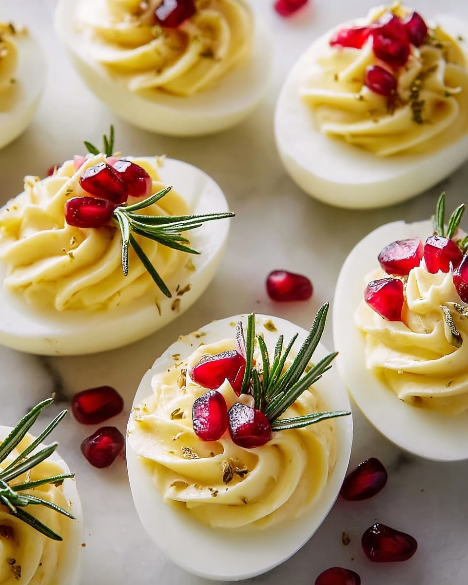 The image shows halved boiled eggs with a smooth white base layer topped with a creamy, swirled yellow filling. Each egg half is decorated with bright red pomegranate seeds and small green rosemary sprigs on top, adding color contrast and texture. The eggs are arranged closely on a white marbled surface. The light highlights the glossy seeds and the soft texture of the filling clearly, creating a fresh and vibrant look. Photo taken with an iphone --ar 4:5 --v 7